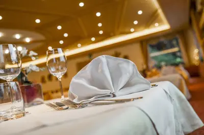 a table with a white napkin and glasses on it at Hotel La Pineta in Selva di Val Gardena