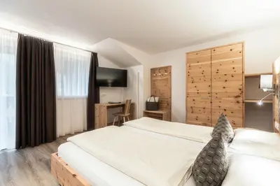 a bedroom with a large white bed and a desk at Hotel La Pineta in Selva di Val Gardena