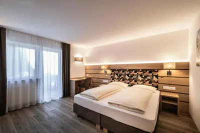 a bedroom with a large bed and a large window at Hotel La Pineta in Selva di Val Gardena