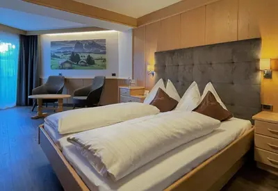 a bedroom with two beds in a hotel room at Hotel Condor in Selva di Val Gardena