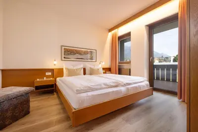 a hotel room with a bed and a large window at Residence Pollingerhof in Merano
