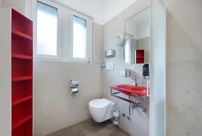 a bathroom with a toilet and a red sink at Hotel Ariston in Bolzano