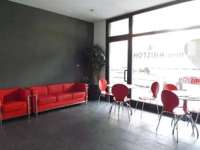 a red couch in a room with a table and chairs at Hotel Ariston in Bolzano