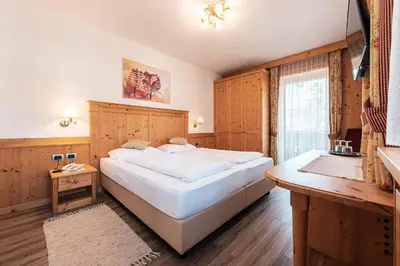 a bedroom with a large white bed and a window at Hotel Goldene Rose in Monguelfo