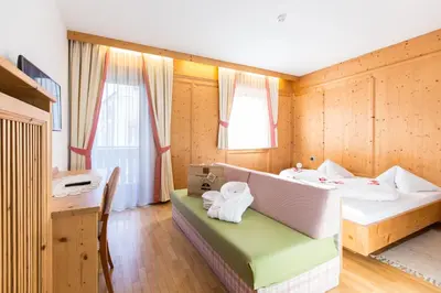 a room with a bed and a desk and a table at Hotel Goldene Rose in Monguelfo