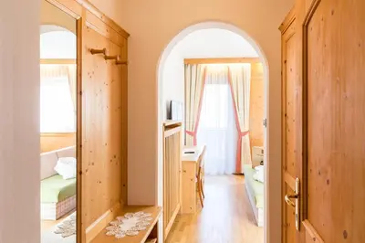 a room with an archway and a bedroom with a desk at Hotel Goldene Rose in Monguelfo