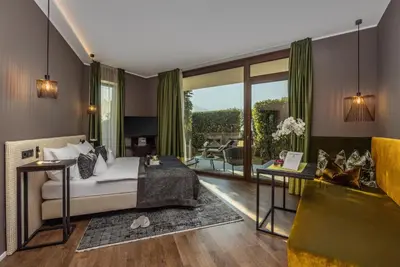 a bedroom with a bed and a living room at SOLEA SÜDTIROL Boutique Hotel in Schenna