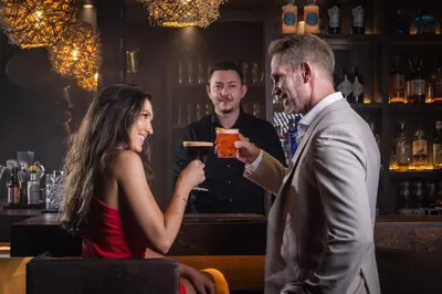 a man handing a woman a drink at a bar at SOLEA SÜDTIROL Boutique Hotel in Schenna