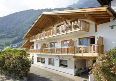 a large building with a balcony and mountains in the background at Apartments Oberdorner in Lagundo