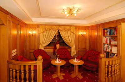 a living room with red chairs and a chandelier at Alpentirolis in Tirolo