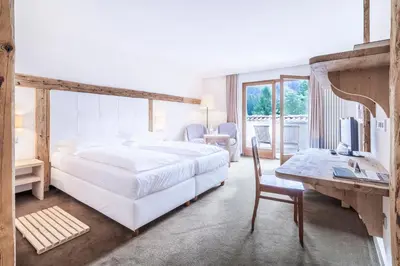 a bedroom with a large white bed and a desk at Hotel Bad Schörgau in Sarntal