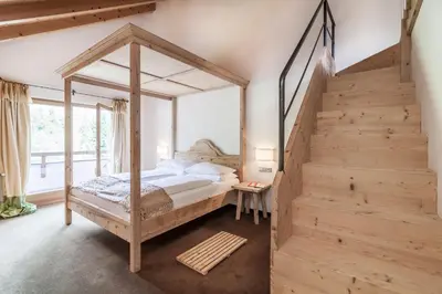 a bedroom with a canopy bed and a staircase at Hotel Bad Schörgau in Sarntal