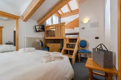a room with two beds and a bunk bed at Hotel Valacia in Pozza di Fassa