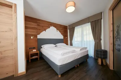 a bedroom with a bed and a window at Hotel Valacia in Pozza di Fassa