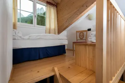 a bedroom with a bed and a window at Hotel Valacia in Pozza di Fassa