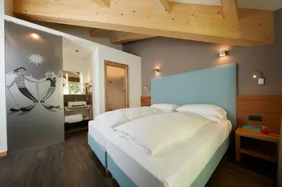 a bedroom with a large white bed in a room at Hotel Valacia in Pozza di Fassa