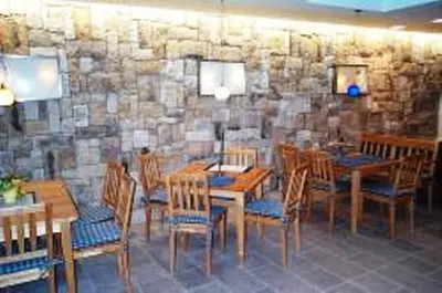 a dining room with wooden tables and chairs and a stone wall at Hubengut Apartments in Lana