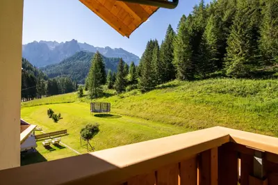 a balcony with a view of a field with a bench at Hotel Somont in Selva di Val Gardena