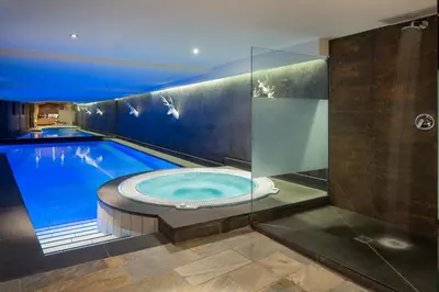 a swimming pool with a jacuzzi tub at Hotel Somont in Selva di Val Gardena