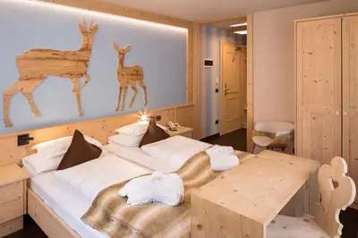 a bedroom with a bed and a table with towels at Hotel Somont in Selva di Val Gardena