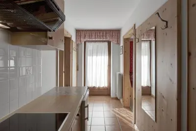 a kitchen with a counter and a hallway with windows at Residence Dolomieu in San Cassiano