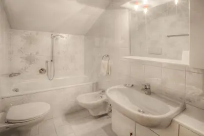 a white bathroom with a toilet and a sink at Residence Dolomieu in San Cassiano