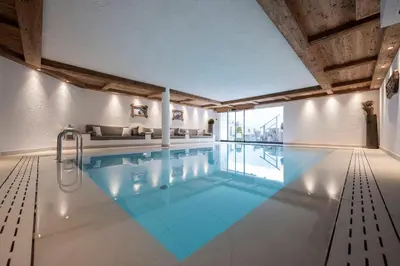 a large swimming pool with blue water in a building at Residence Cesa Sassela in Ortisei