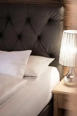 a bed with a black headboard and a table with a lamp at Residence Cesa Sassela in Ortisei