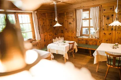 a dining room with two tables and two windows at Hotel Kiendl in Schenna
