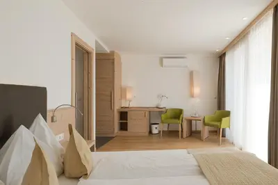 a bedroom with a bed and a table and chairs at Hotel Kiendl in Schenna