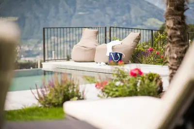 a bench with pillows and flowers on a balcony at Hotel Kiendl in Schenna