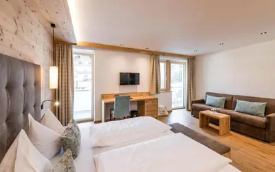 a living room with a bed and a couch and a desk at Hotel Waldsee in Fiè