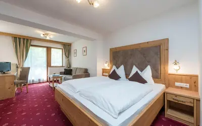 a hotel room with a large bed and a desk at Hotel Waldsee in Fiè
