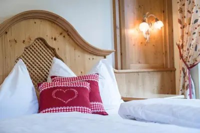 a bed with a red heart pillow on it at Hotel Waldsee in Fiè