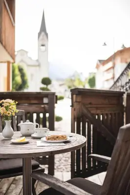 a table with a plate of food on a balcony at Christophorus Mountain Residence in San Vigilio Di Marebbe