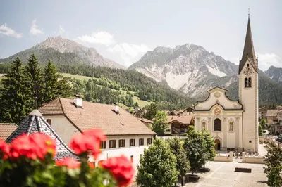 a church in a town with mountains in the background at Christophorus Mountain Residence in San Vigilio Di Marebbe