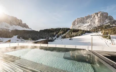 a woman sitting at a table in a restaurant at Hotel Plan de Gralba - das Berghotel in Selva di Val Gardena