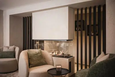 a living room with two chairs and a fireplace at Hotel Plan de Gralba - das Berghotel in Selva di Val Gardena