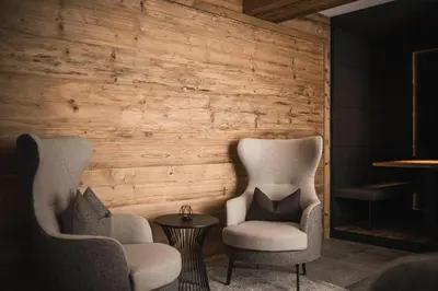 two chairs and a table in front of a wooden wall at Hotel Plan de Gralba - das Berghotel in Selva di Val Gardena