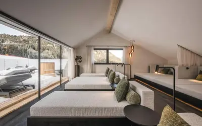 a attic bedroom with two beds and a balcony at Hotel Plan de Gralba - das Berghotel in Selva di Val Gardena