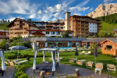 a large swimming pool on top of a building with mountains at Hotel Fanes in San Cassiano