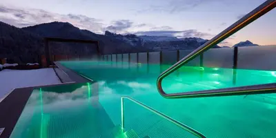 a hotel swimming pool with mountains in the background at Hotel Fanes in San Cassiano