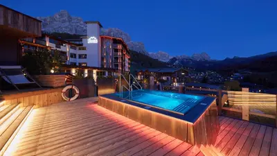 a heated plunge pool with snow covered mountains in the background at Hotel Fanes in San Cassiano