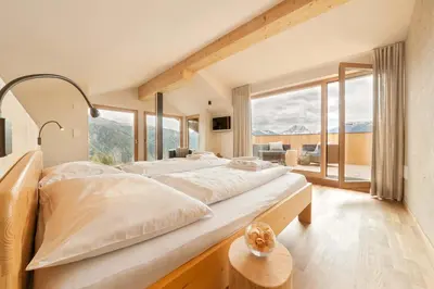 a large bed in a room with large windows at Herol - my mountain retreat in Luson