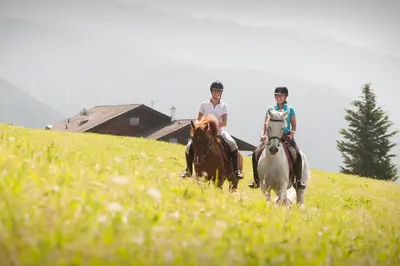 two people riding horses on a grassy hill at Herol - my mountain retreat in Luson