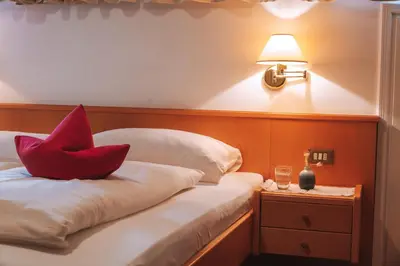 a bedroom with a red pillow on a bed at Pension Lafod in Tirolo
