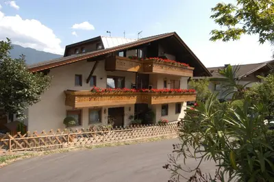 a building with a balcony with red flowers on it at Pension Lafod in Tirolo