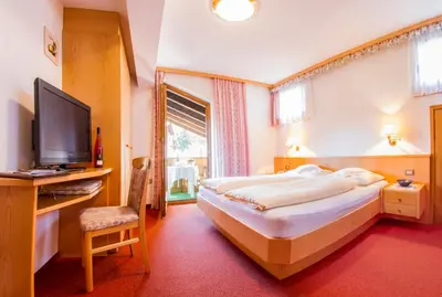a bedroom with a large bed and a television at Pension Lafod in Tirolo