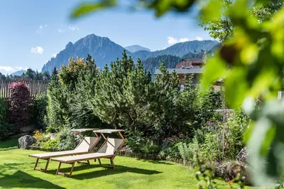 a bench in a garden with mountains in the background at Sporthotel Exclusive in San Vigilio Di Marebbe