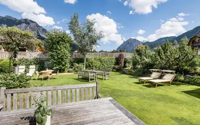 a garden with chairs and a table in the grass at Sporthotel Exclusive in San Vigilio Di Marebbe